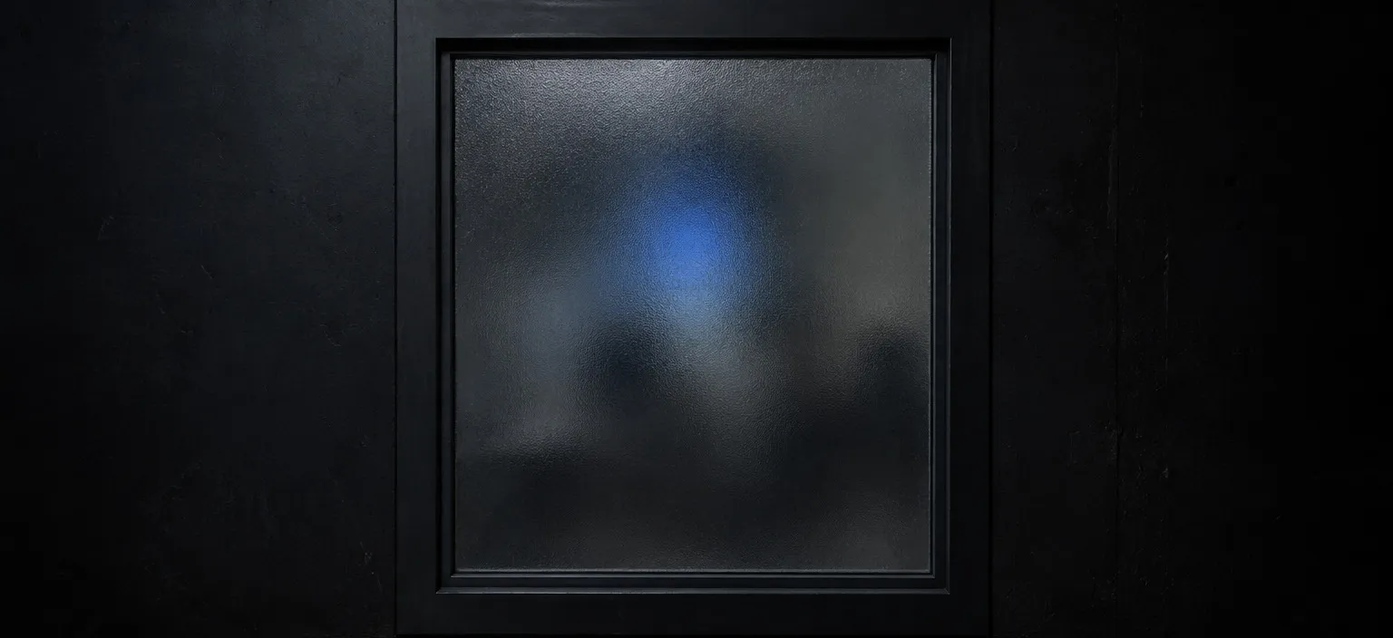 A frosted glass pane lit from behind, the shapes beyond it present but unreadable